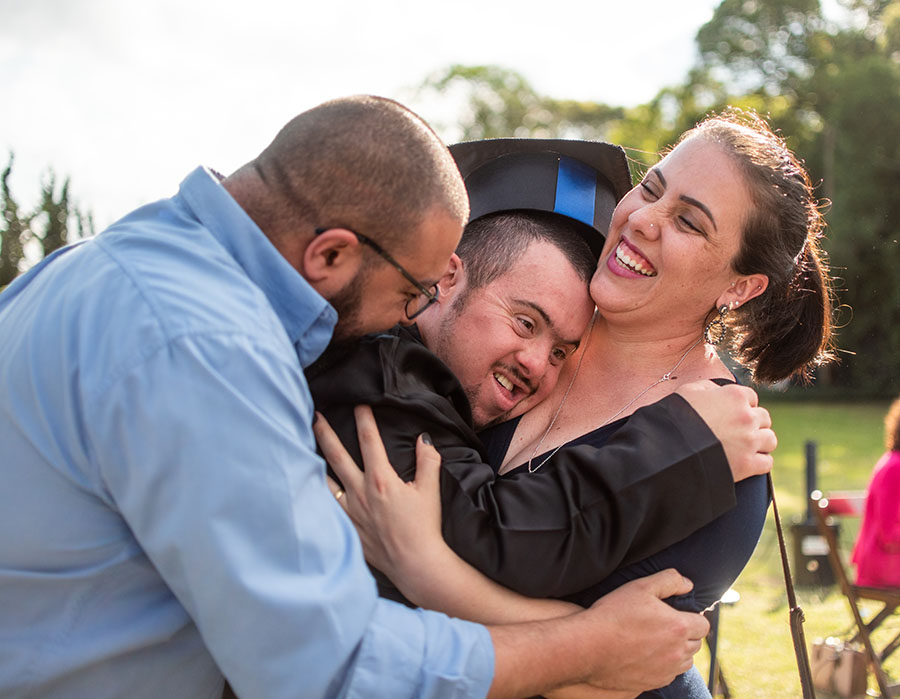 parents hugging child in graduation gown