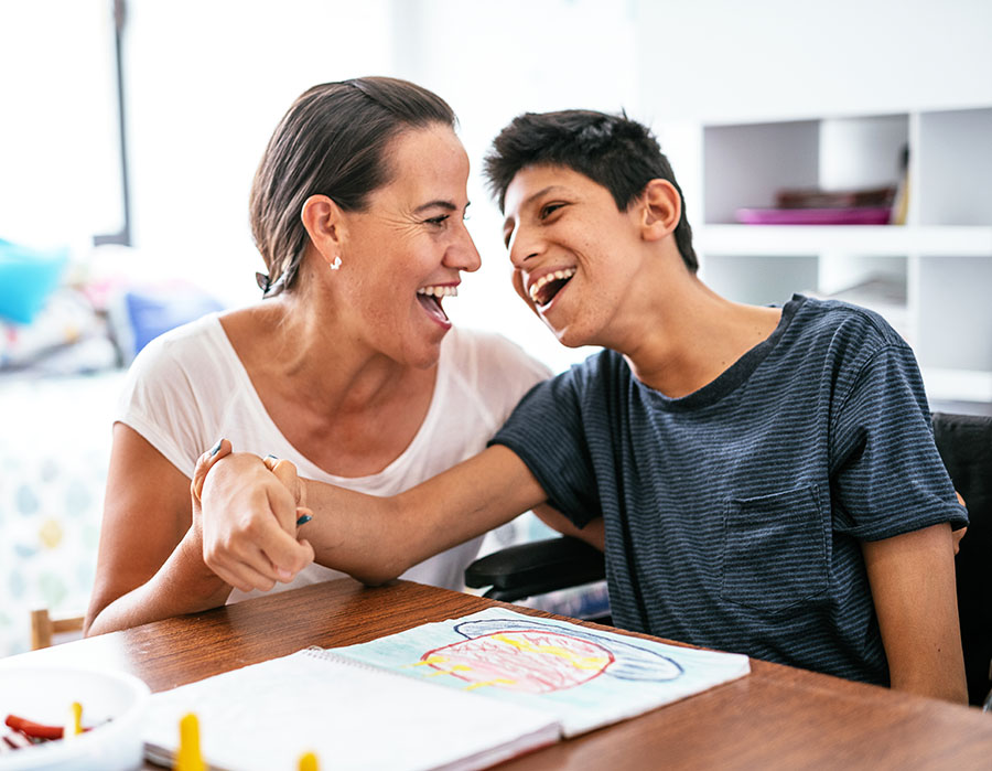 Disabled Latino teenager with Celebral Palsy and mother laughing.