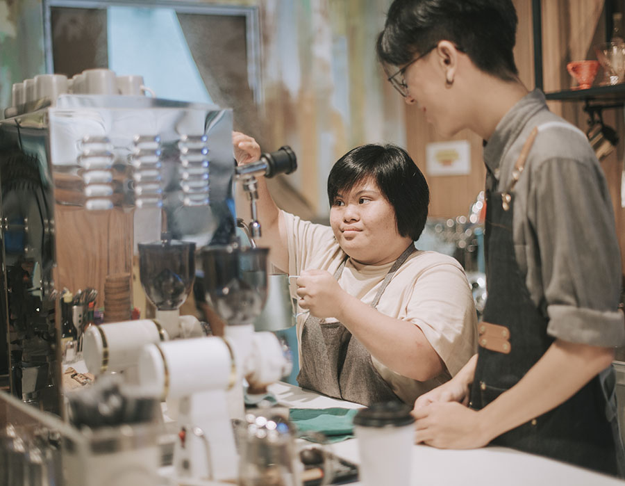 female learning from barista making coffee in her café place of work