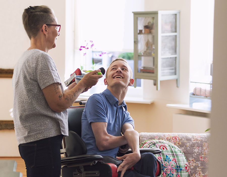 Color image of a real life young physically impaired Cerebral Palsy patient being fed by his mother.