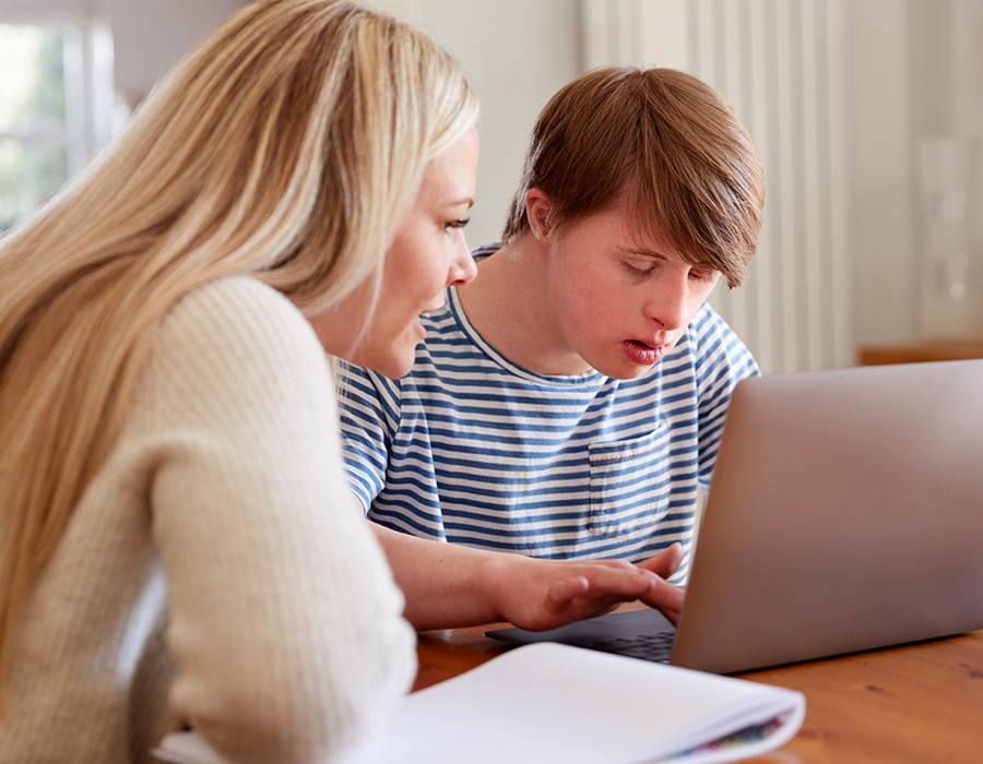 teen working on laptop with woman looking on